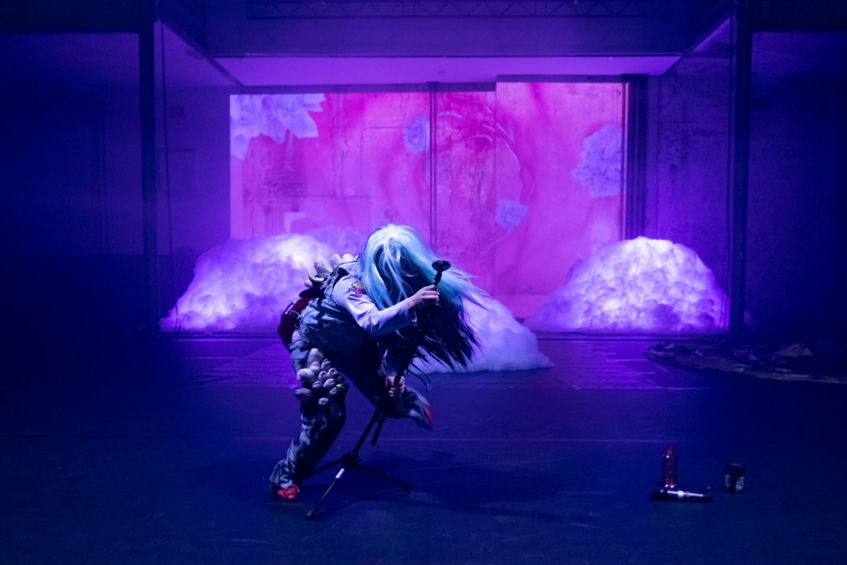 Olivia Hyunsin Kim in einem Fellkostüm greift schwungvoll nach einem Mikrofon