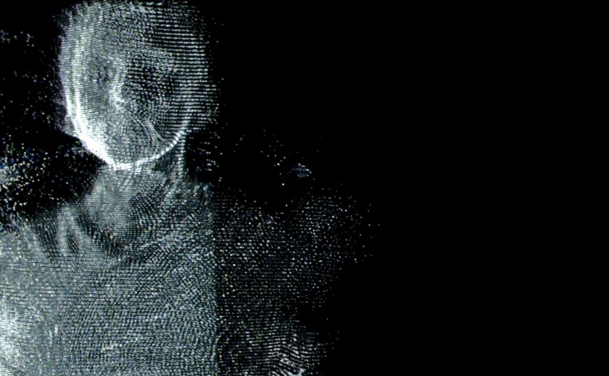 Eine Hologramm-ähnliche Gestalt, die aus einer grünlichen Pixelwolke besteht