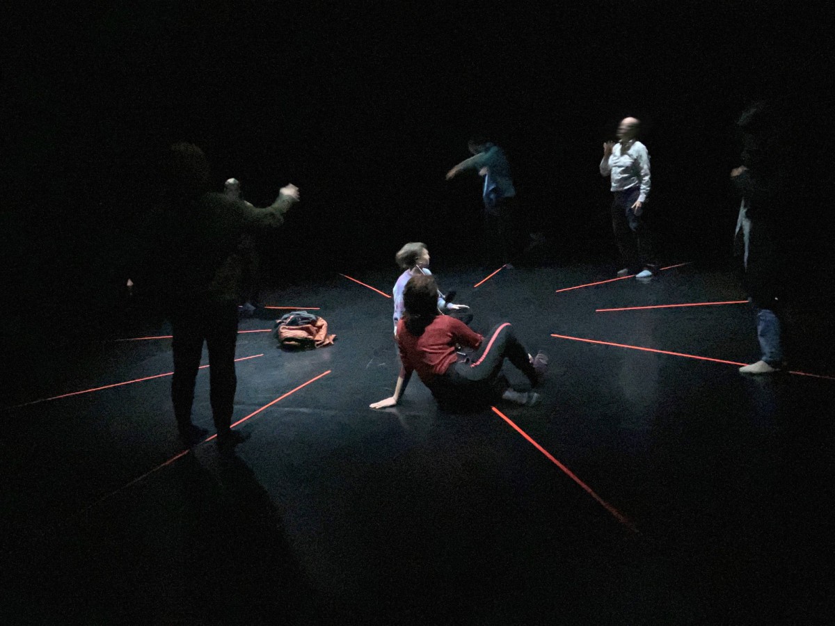 Eine Gruppe Menschen im Kreis auf einer dunklen Bühne