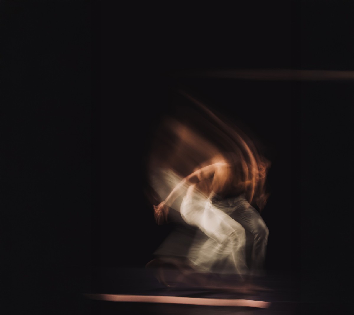 A photo with motion blur that gives a glimpse of a dancing Black person