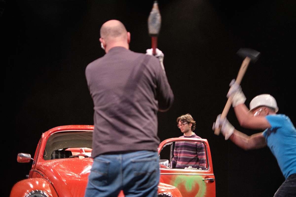 Several people are hitting a car with tools.