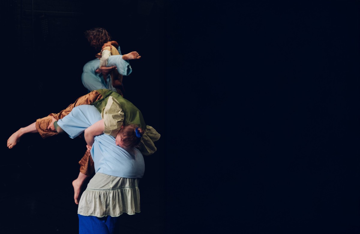 Drei Tänzer*innen, wie eine Statue ineinander verschlungen