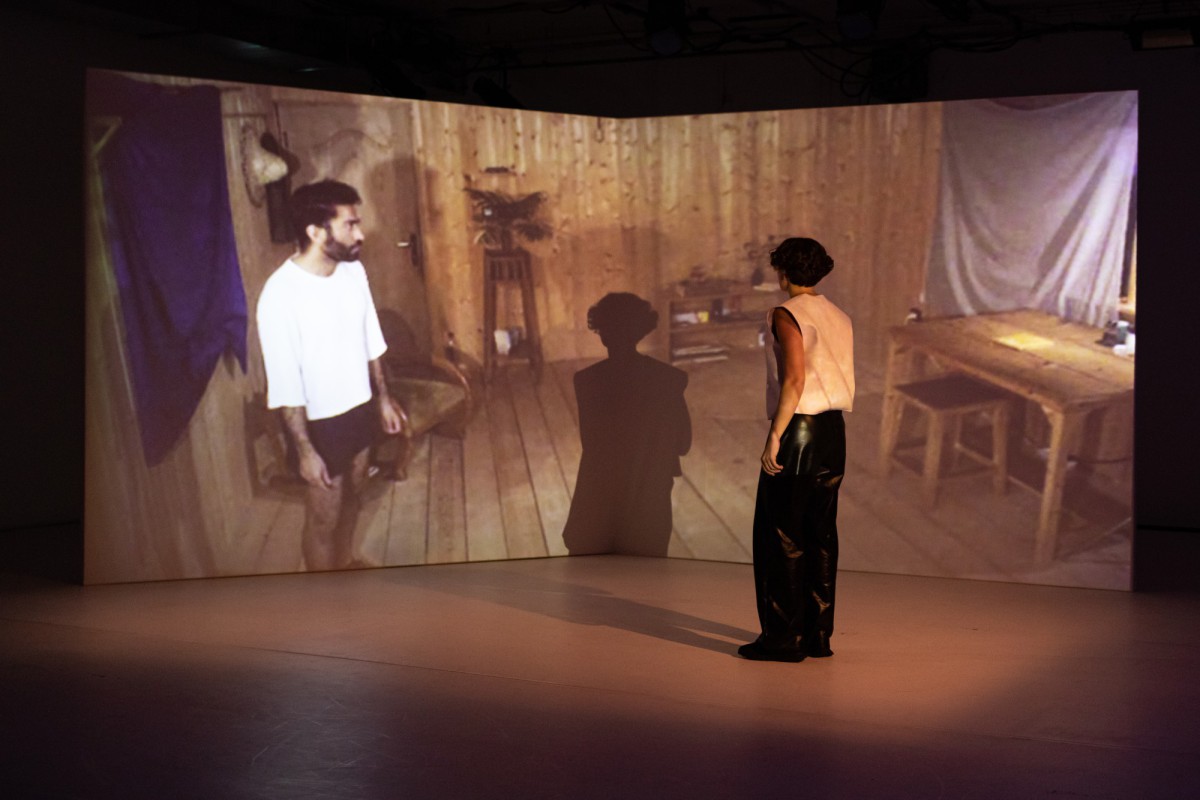 A performer on stage interacts with a projected person
