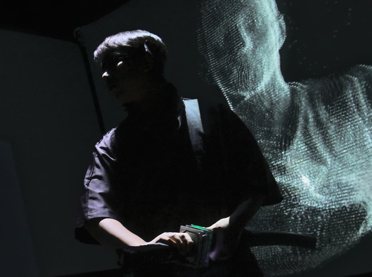 A person stands in front of a screen showing a digital figure.