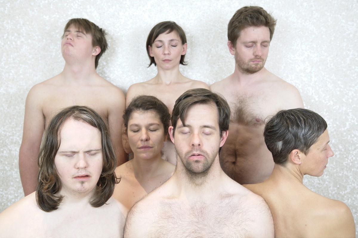 6 Performerinnen stehen in einer Gruppe zusamme mit nackten Oberkörpern und geschlossenen Augen
