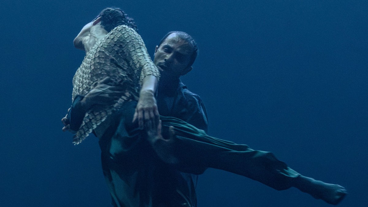 Zwei Tänzer*innen, einer hebt den anderen nach oben.