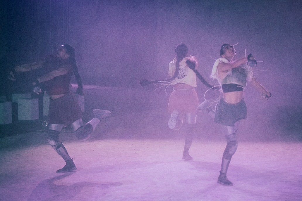 Drei tanzende Personen in violett-dunstiger Atmosphäre